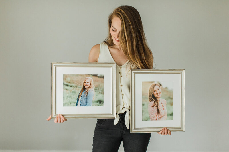 woman holding 2 silver frames each containing a portrait of two teenage sisters