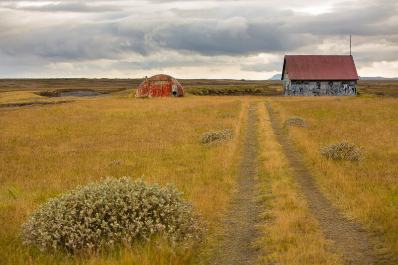 Open field with gravel road and old barns