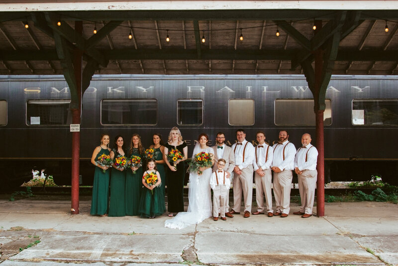 wedding party smiling in front of train