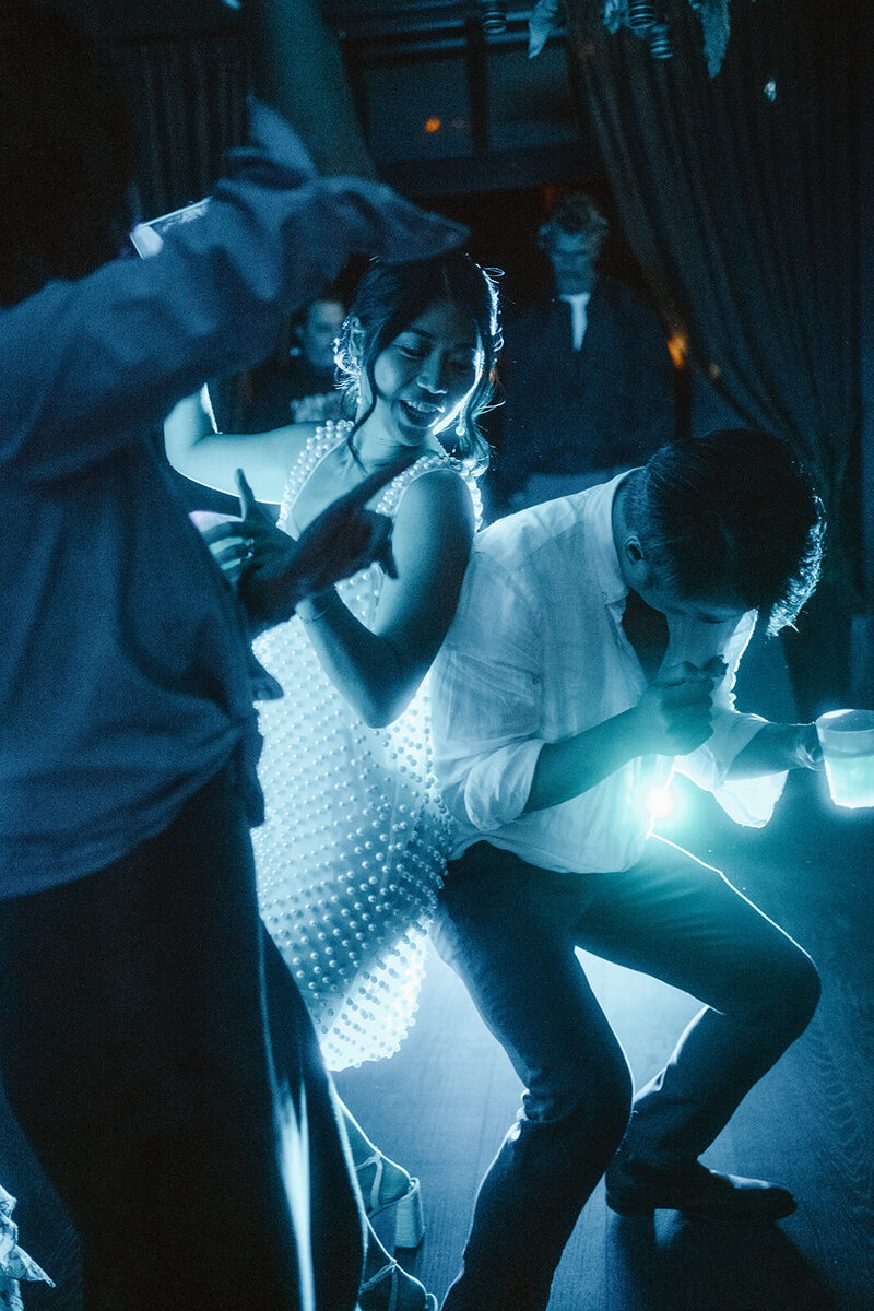 Reportage photo of the bride dancing at a wedding party at Nordelaia, with a blue light from behind