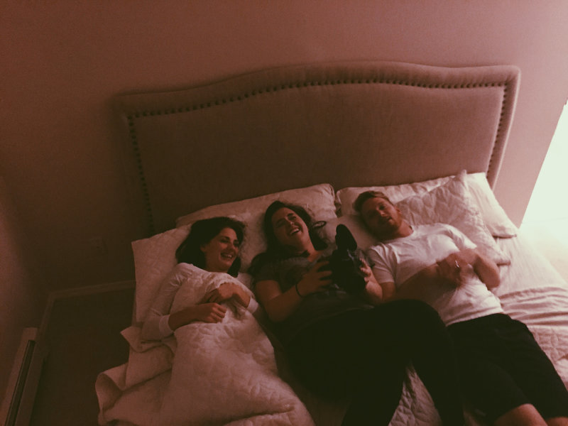 lauren roberts lays in bed with couples laughing