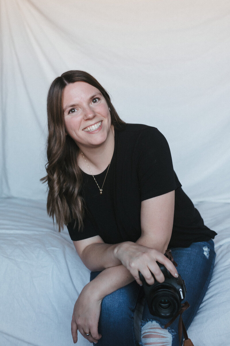 Savannah, a birth and motherhood photographer, smiling with camera in hand