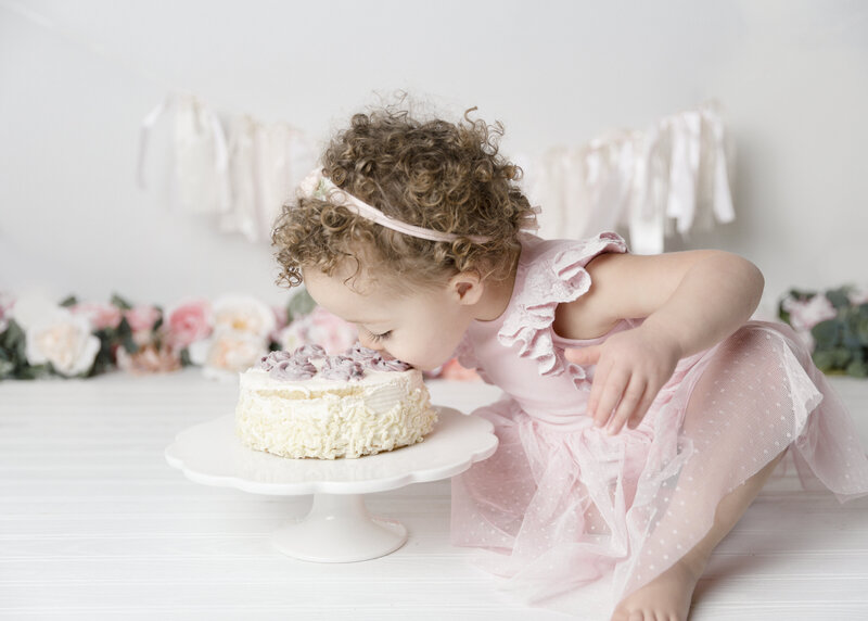 Baby girl putting her face to the cake