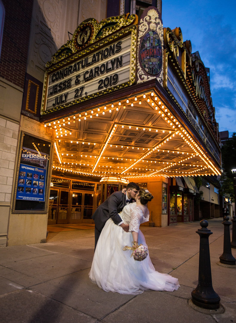 bride and groom kiss under the marquee at the Warner Theatre in Erie, PA