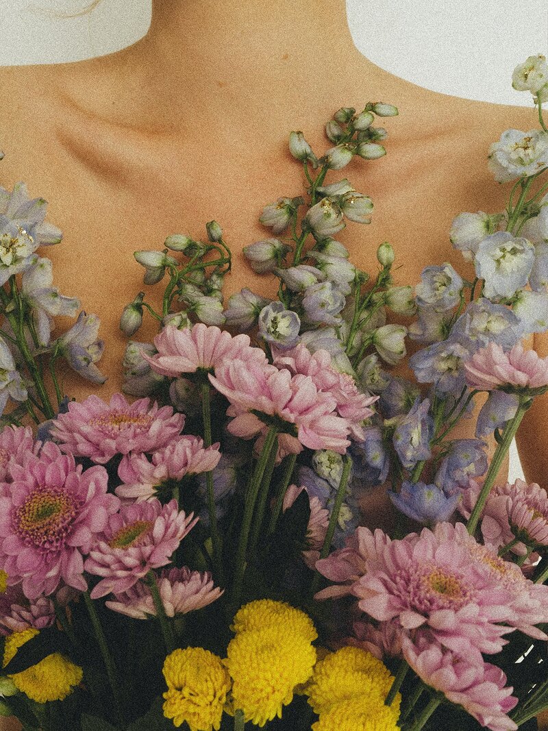 close-up of a woman holding flowers against her body
