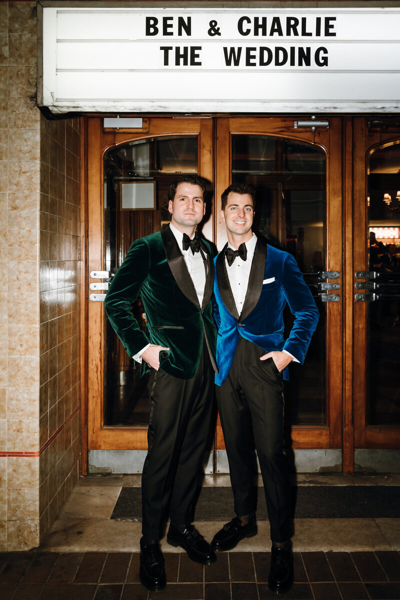 grooms in velvet suits outside their cinema wedding