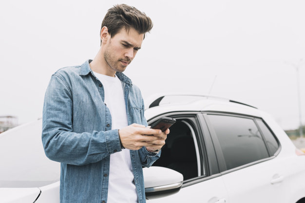 young-man-texting-message-cellphone-standing-near-car-window_23-2147937314