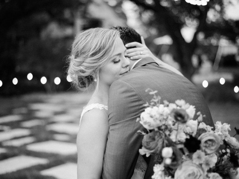 Groom hugs bride from back with flowers