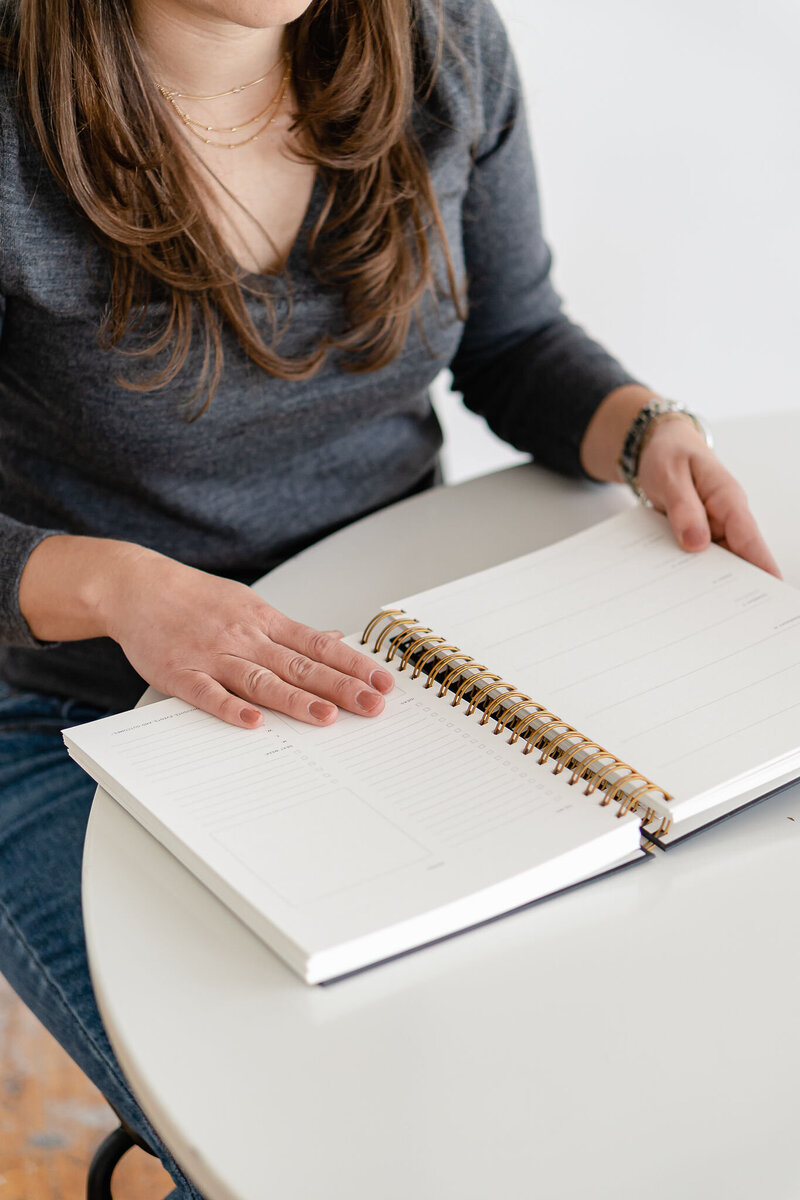 small business owner writes out to do list on planner
