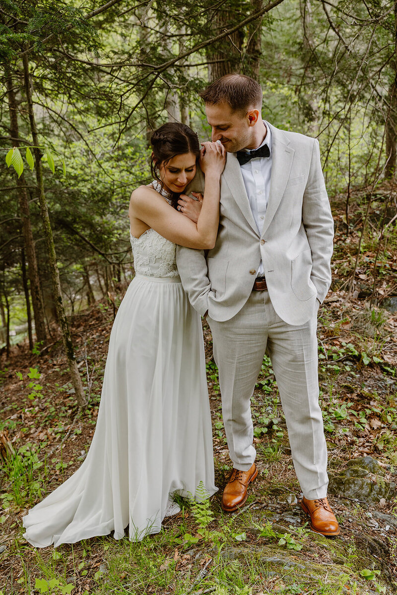 A couple stands in the PA forest during their elopement with family. 
