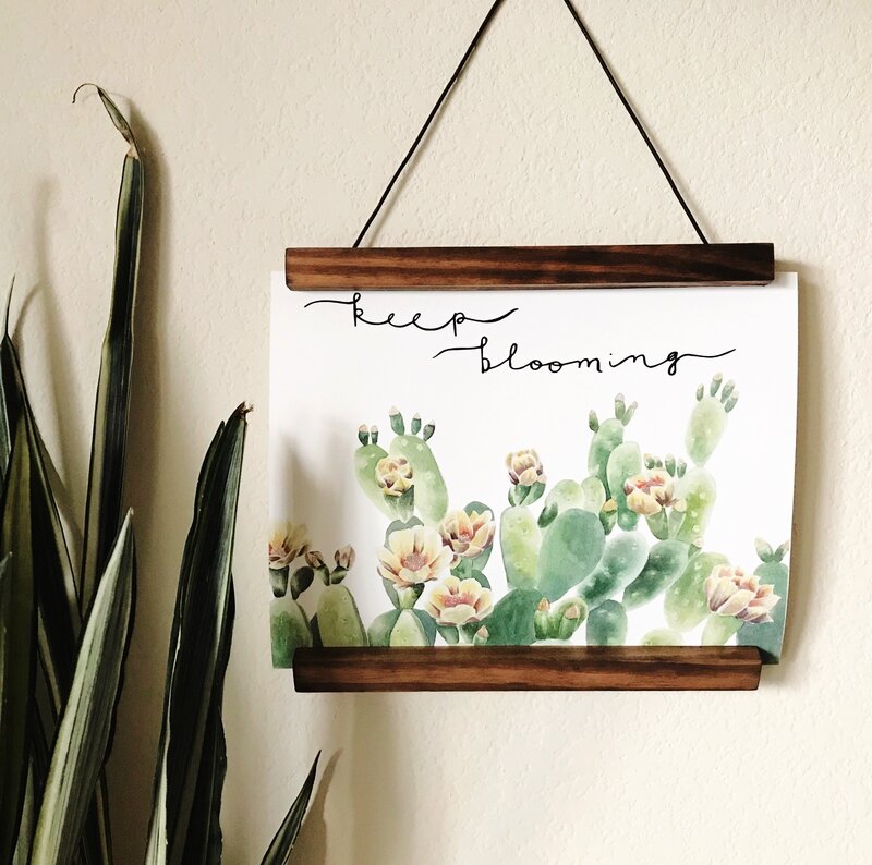 Hanging art print with plants that says "keep blooming"
