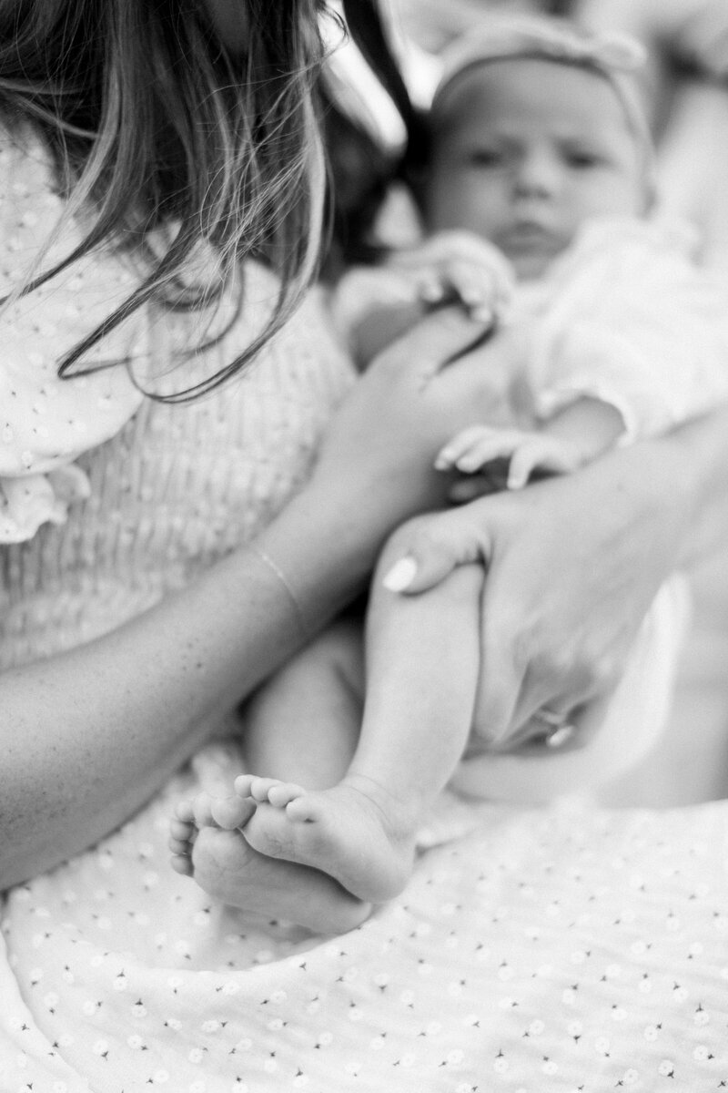 Black and white image of mother's hands holding her baby's hands and feet