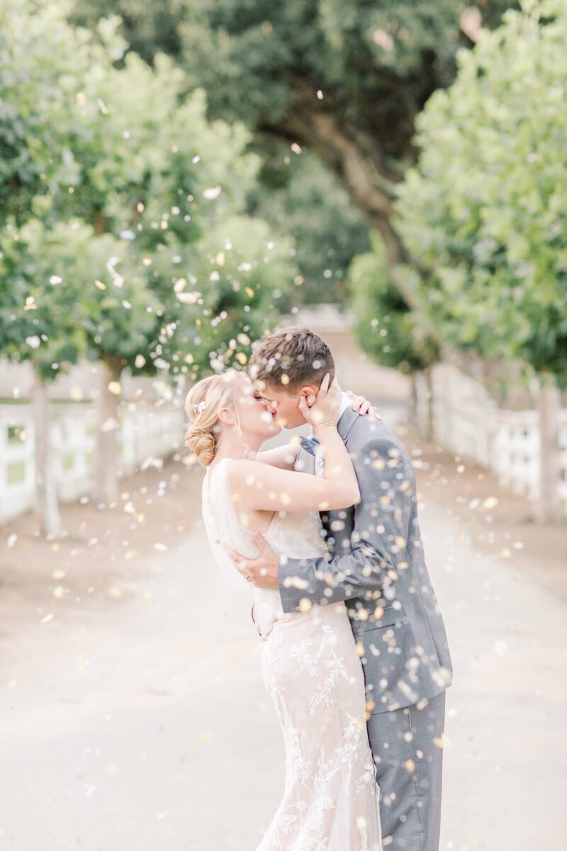 Bride and groom kiss with confetti