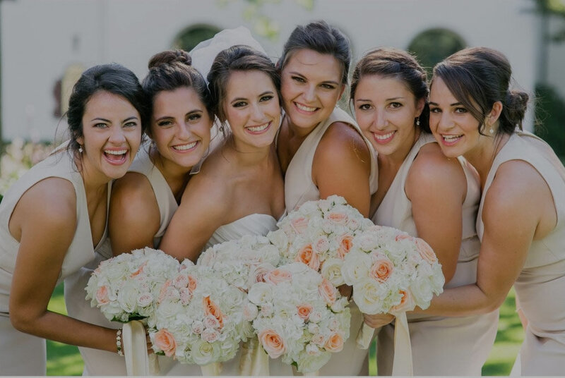 group of bridesmaids with bride showing hair makeup and flowers
