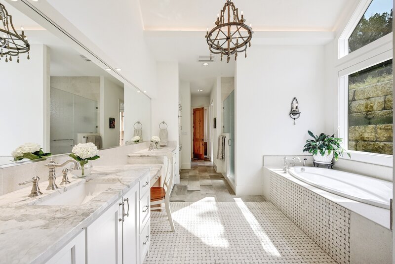 Large white bathroom with beige countertops and a chandelier