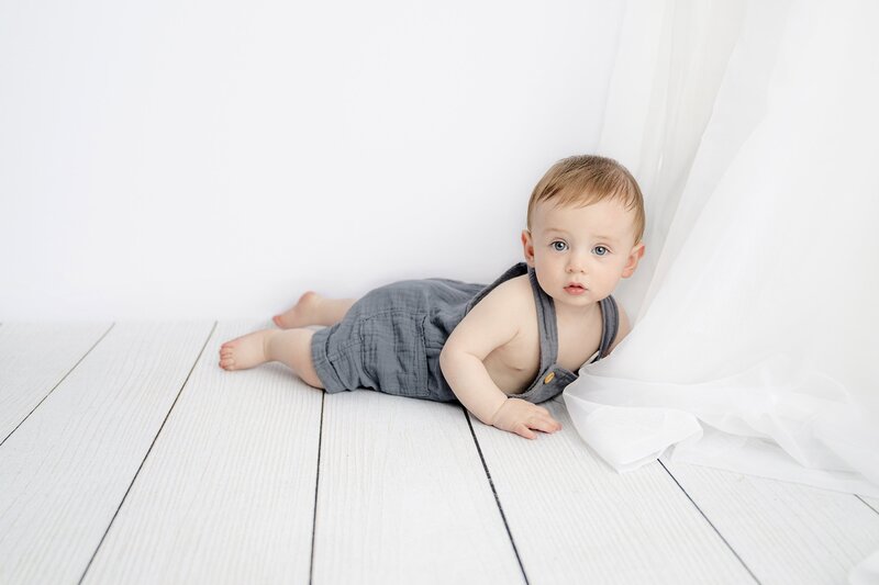 seven month old sitter session with a little boy laying on his belly in a white background