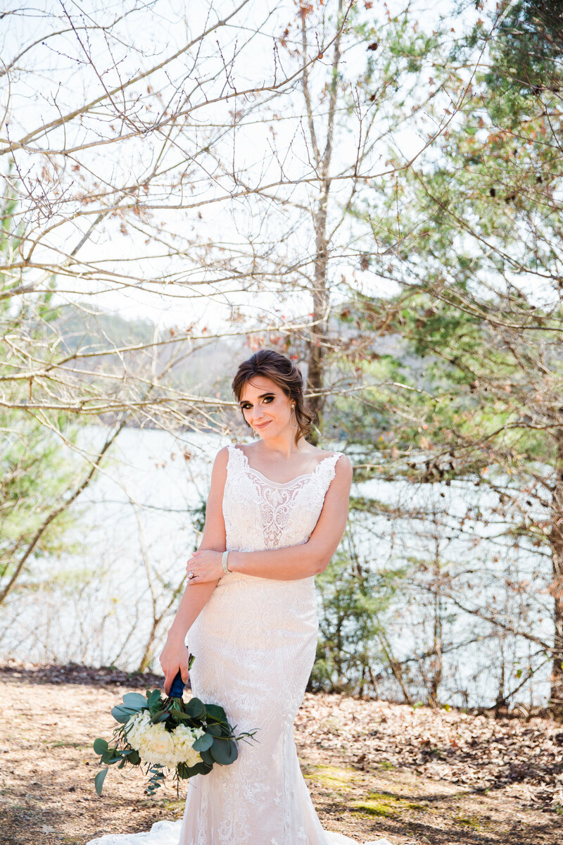 bride holding a bouquet next to a lake