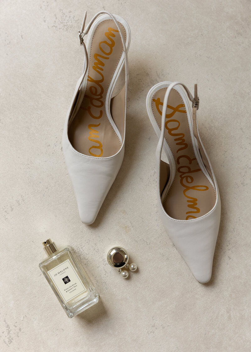 An iconic shot of luxury heels for the bride on her wedding day complimented with the pearl earrings and perfume that she will be wearing.