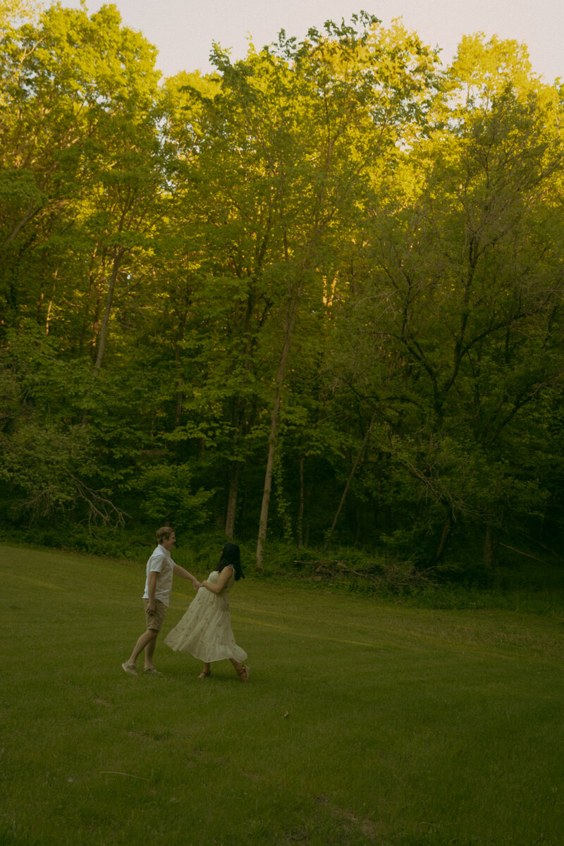 Newlyweds gaze into eachothers eyes on a brisk summer evening while the sun glares between their faces and her veil gets carried in the wind