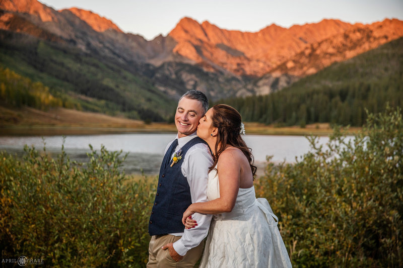 Bride kisses groom with orange color on the Gore Range on wedding day at Piney River Ranch