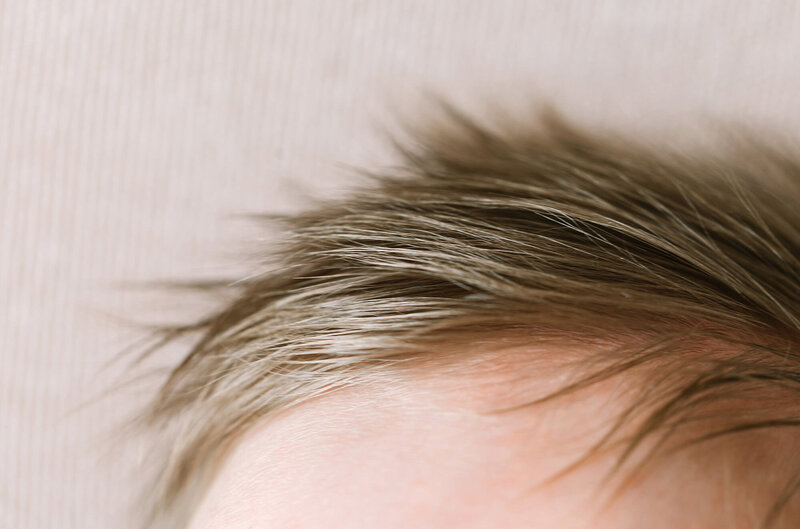 A close up image of a newborn baby's light brown hair