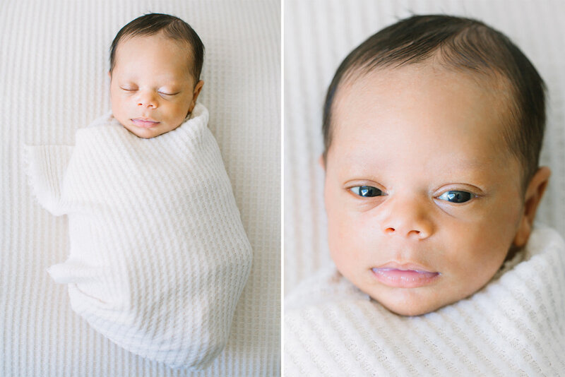 A newborn baby in a white swaddle with his eye open and looking at the camera.