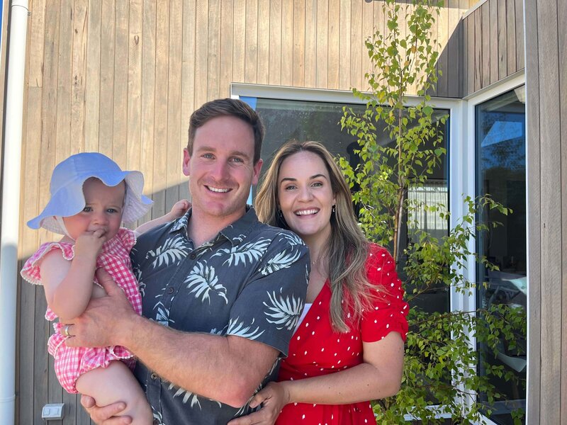 Brent, Isabelle McNeil and their Daughter smiling in front of their custom home
