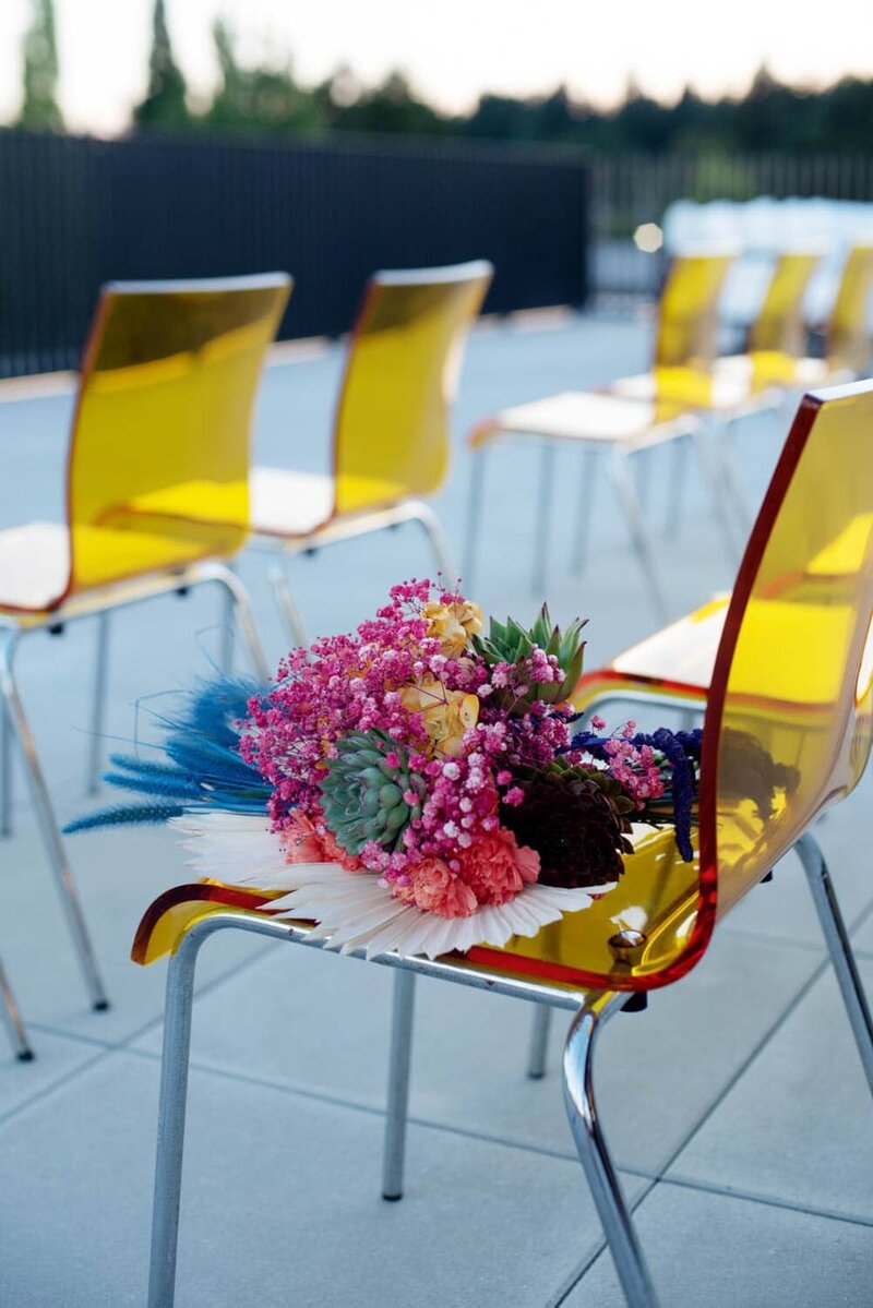 a vibrant bouquet sits on a yellow mod chair