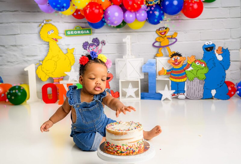 charlotte girl sits with her hand on her birthday cake in her themed smash