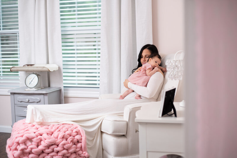 A woman sitting with her legs up and holding her baby girl in the nursery.