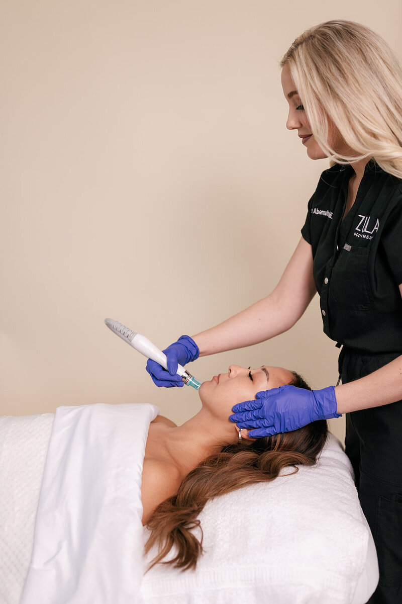 Woman laying on a medspa table receiving a facial treament from a practitioner