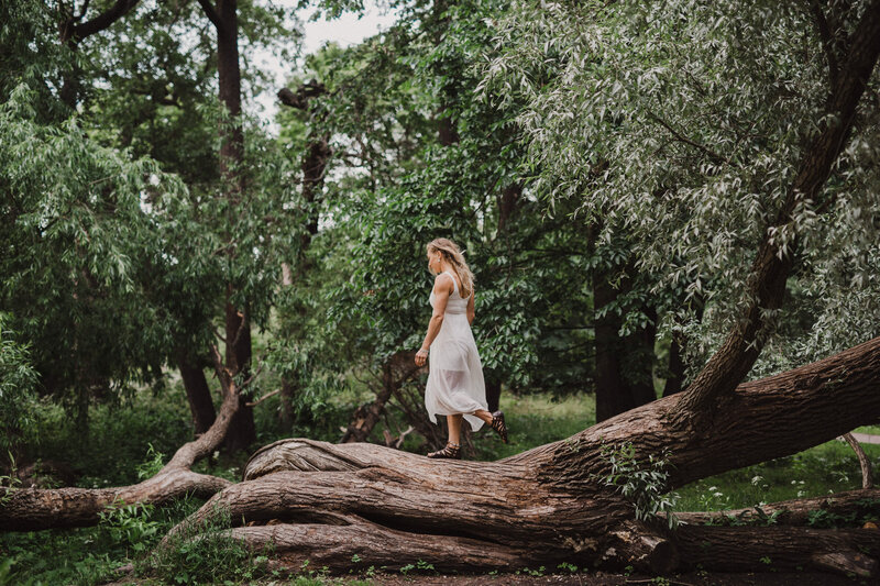 Nainen kävelee maata pitkin kasvavaa puuta pitkin Lapinlahdenpuistossa Helsingissä