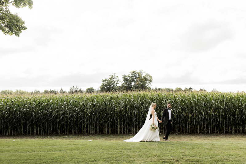 bride and groom walk through field at Barn 1906