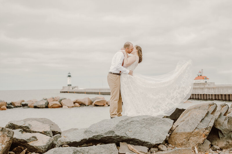 Bride and groom kissing on Canal Park overlooking the lighthouse in Duluth, Minnesota