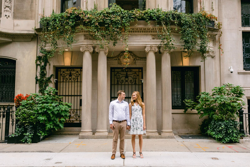 A couple pose in front of a mansion