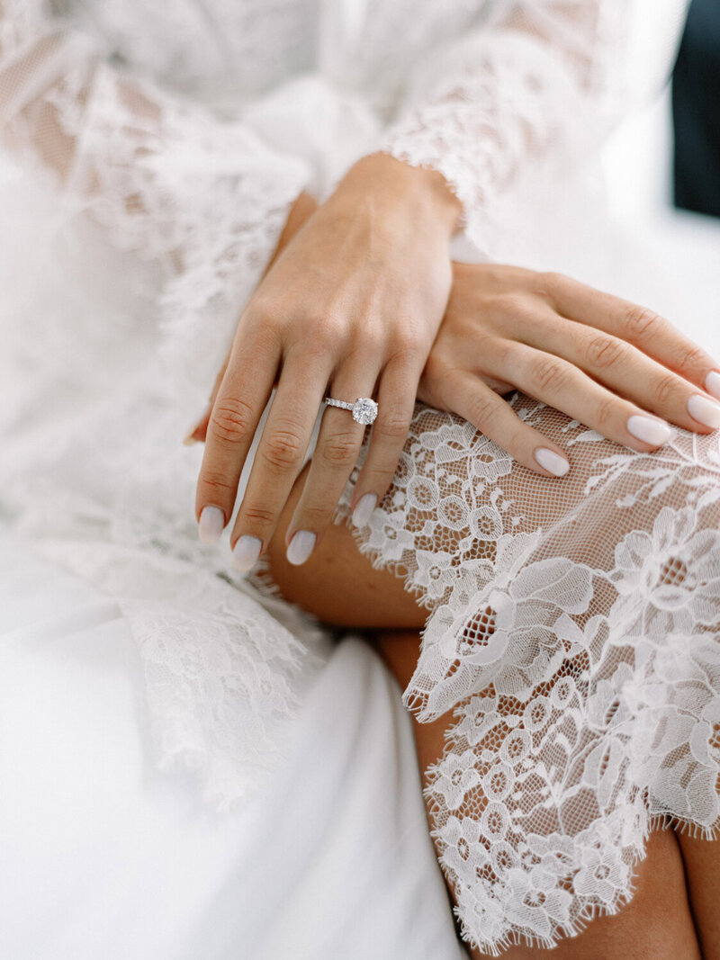 Close up of bride's hands folded over her legs with lace fabrcis