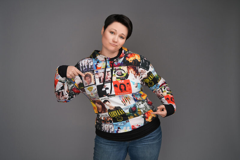 woman wear a 90s band themed hoodie pointing at her shirt