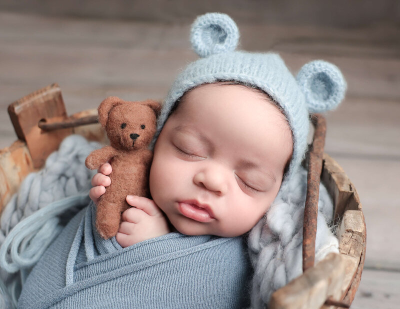 Newborn baby boy holding a bear in our studio in  Rochester, NY.