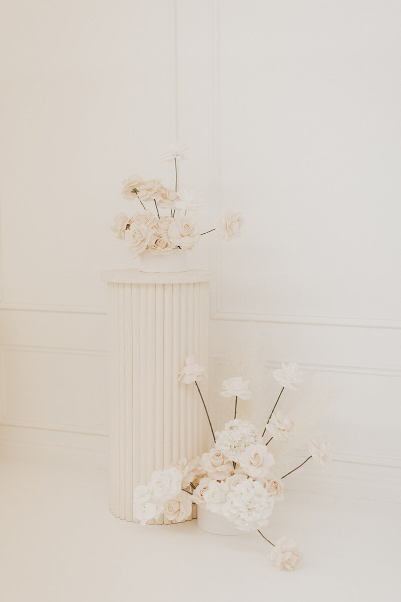 Photographic still life of white roses on a pedestal.
