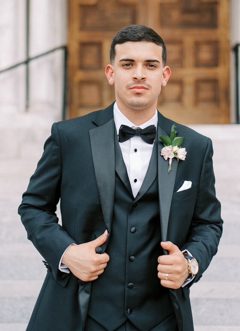 black hair groom where a black three piece suit with a simple floral boutonniere while holding his suit coat smoldering in St. Petersburg Florida