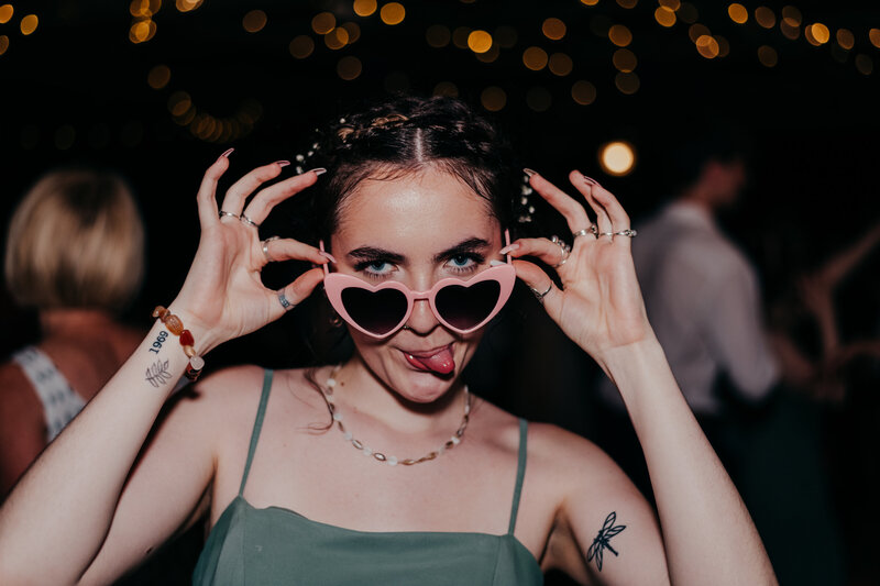 bridesmaid wearing heart glasses at coastal discovery museum wedding reception
