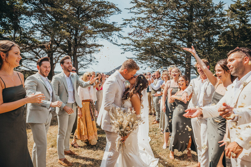 bride and groom kissing underneath confetti
