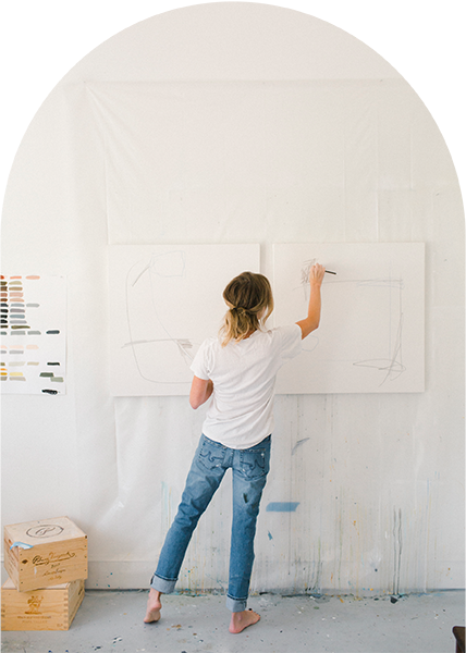 Artist in white studio painting canvases