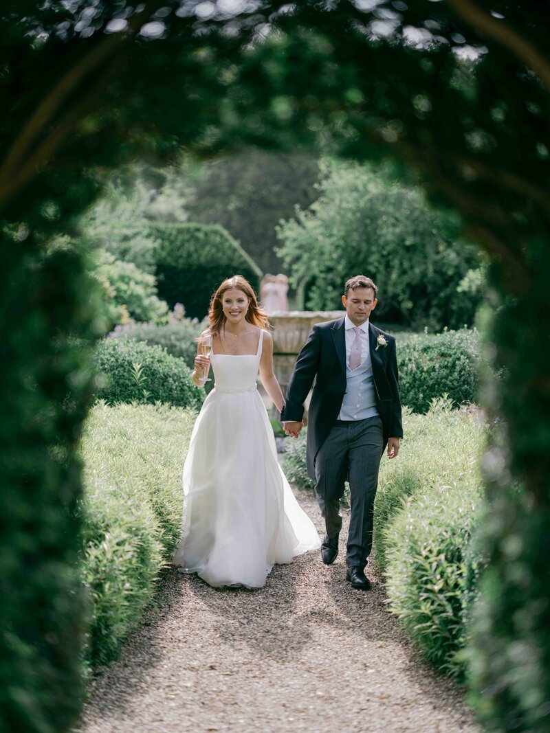 Bride and Groom walking through a greenery arch
