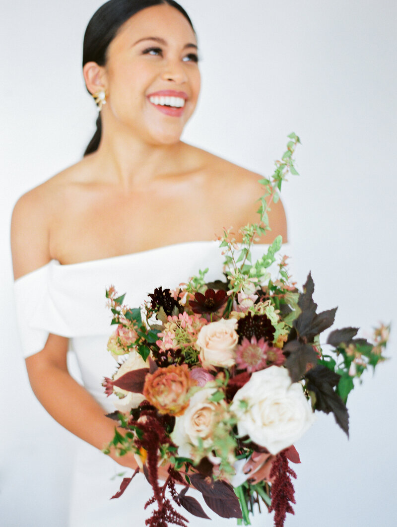 bride holding her bouquet and looking off into the distance laughing and smiling