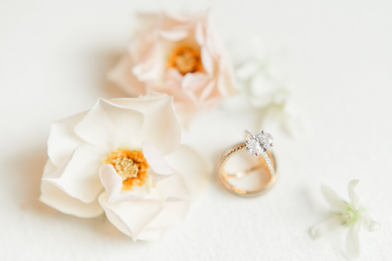 Detail photo of delicate flowers and wedding rings on a white background.