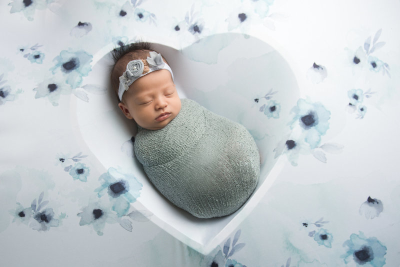 Newborn baby girl swaddled and posed on heart shaped bowl during Point Pleasant studio session.