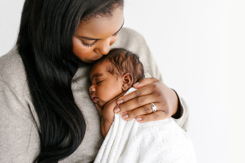Photo of Black mother with baby cuddling on chest