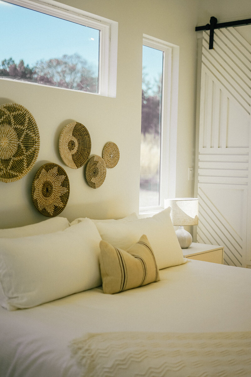 Bedroom with white bed cover and  decorative baskets on the wall