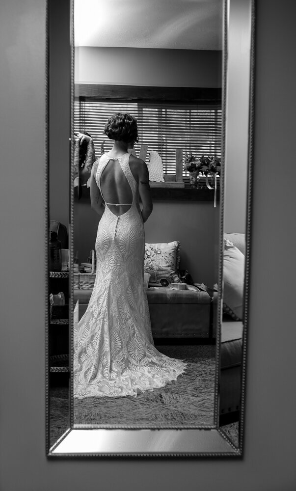 Photo of long mirror reflecting  image of bride in her wedding  dress facing away from the camera